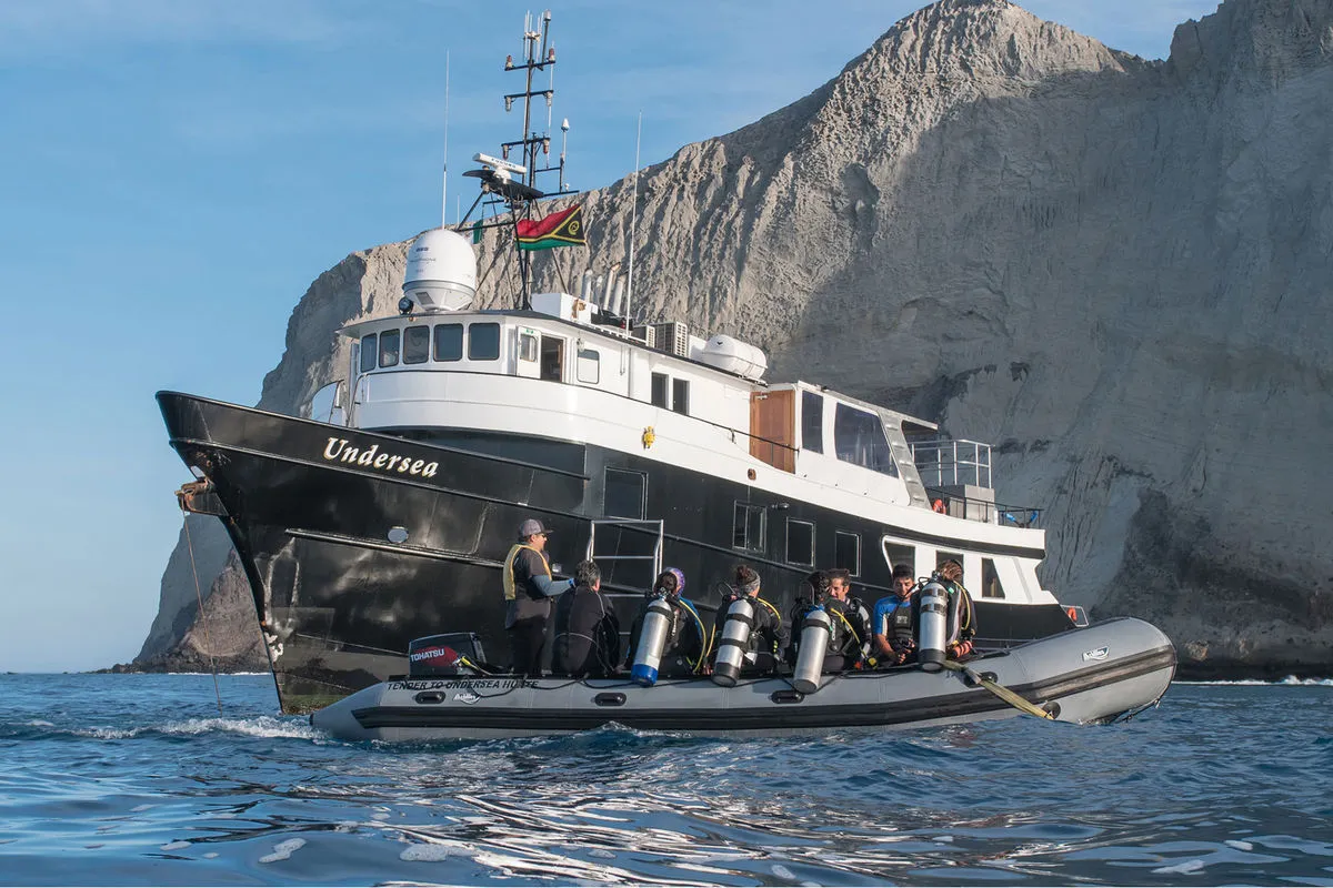 Дайверы в тендере у борта Nautilus Under Sea на фоне отвесной скалы