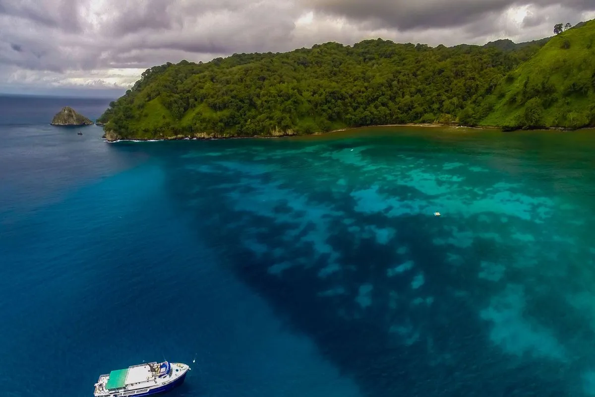 Aerial view of Okeanos Aggressor II over a turquoise Cocos bay