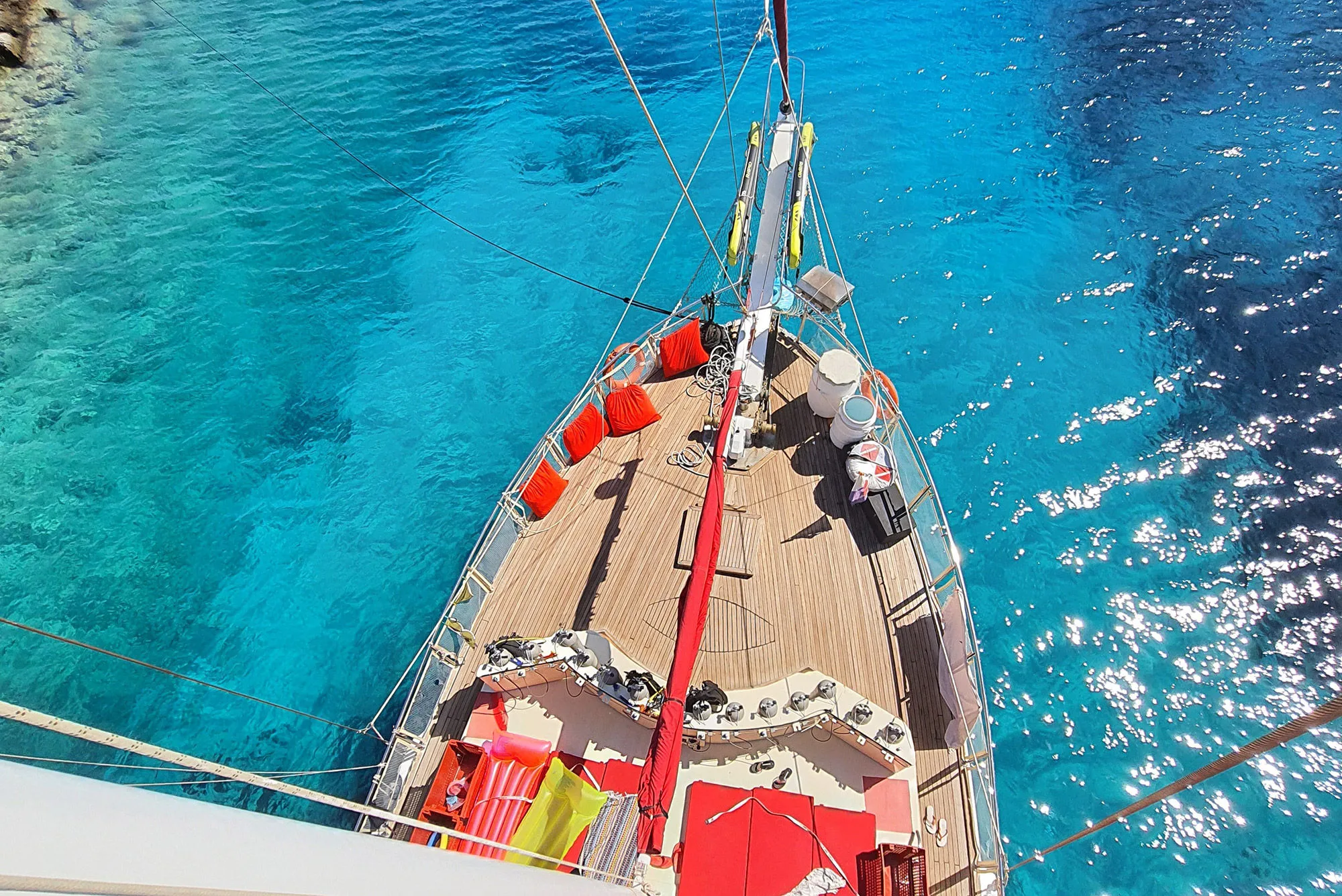 Foredeck sunbathing mattresses shot from the mast above clear water