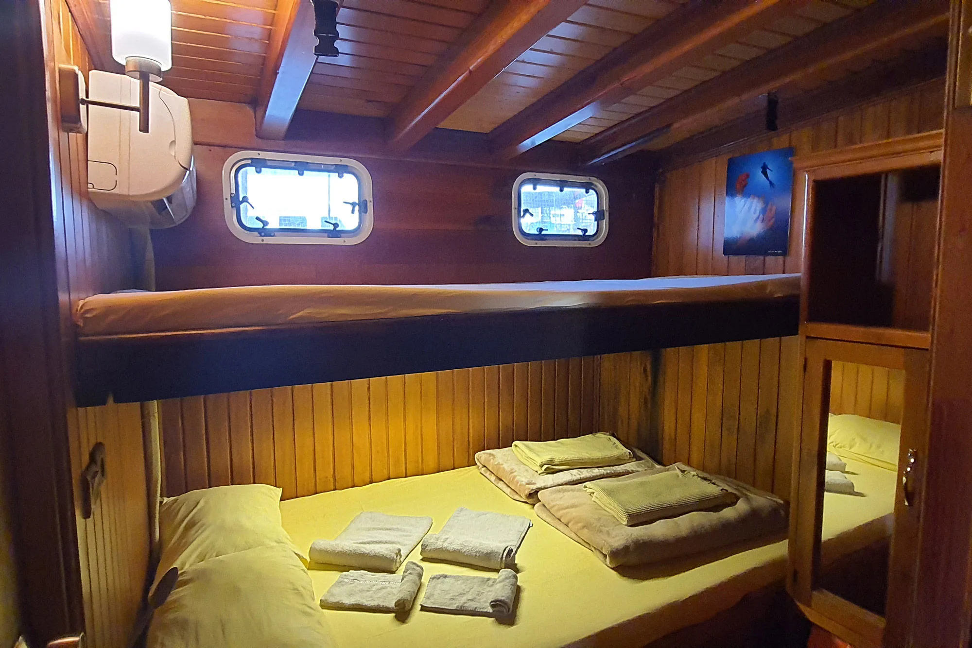 The roomiest Okyanus JD cabin — bed in an alcove with a mirror and round porthole