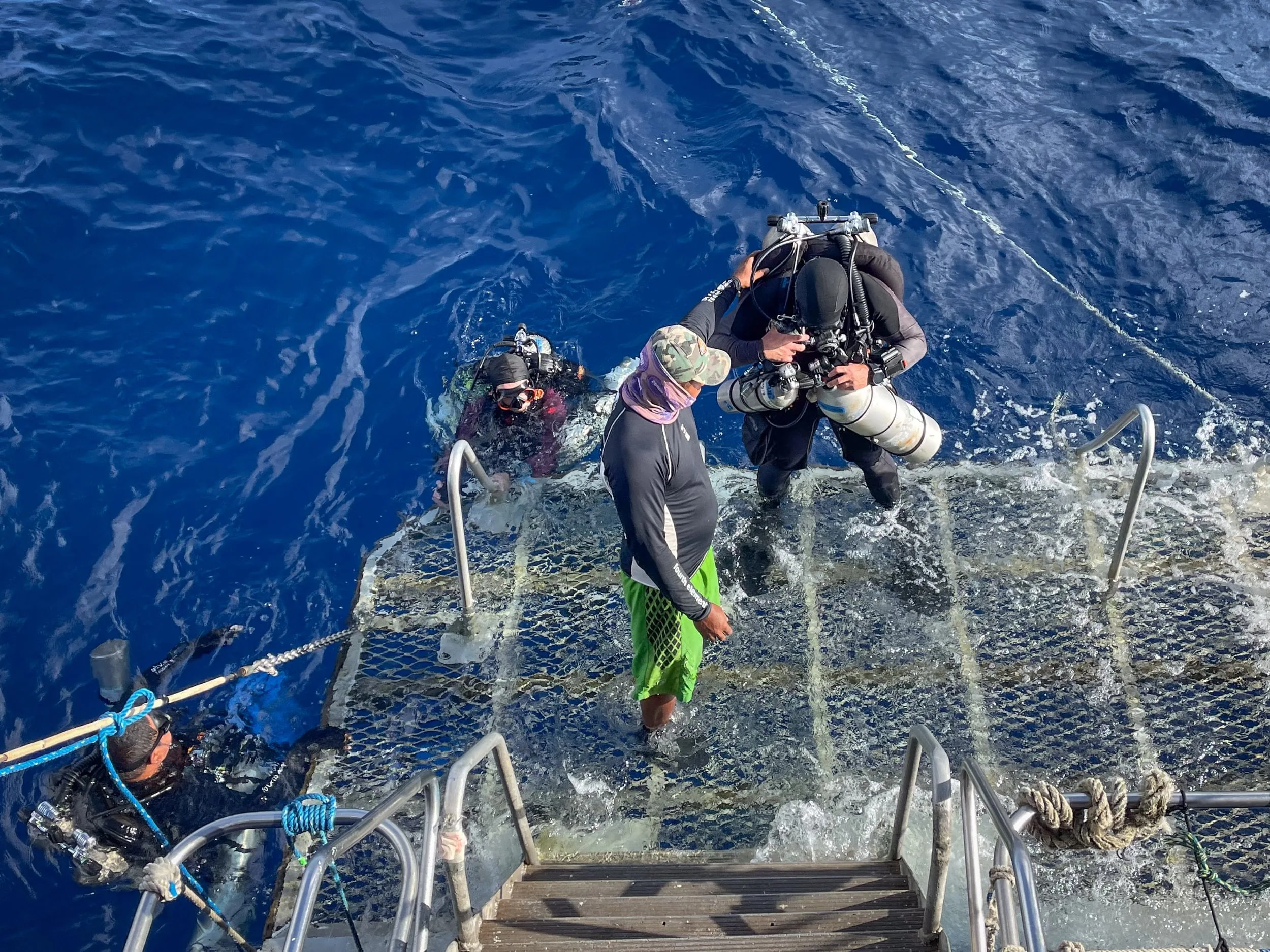 Divers climbing back onto the platform of Pacific Master after a dive