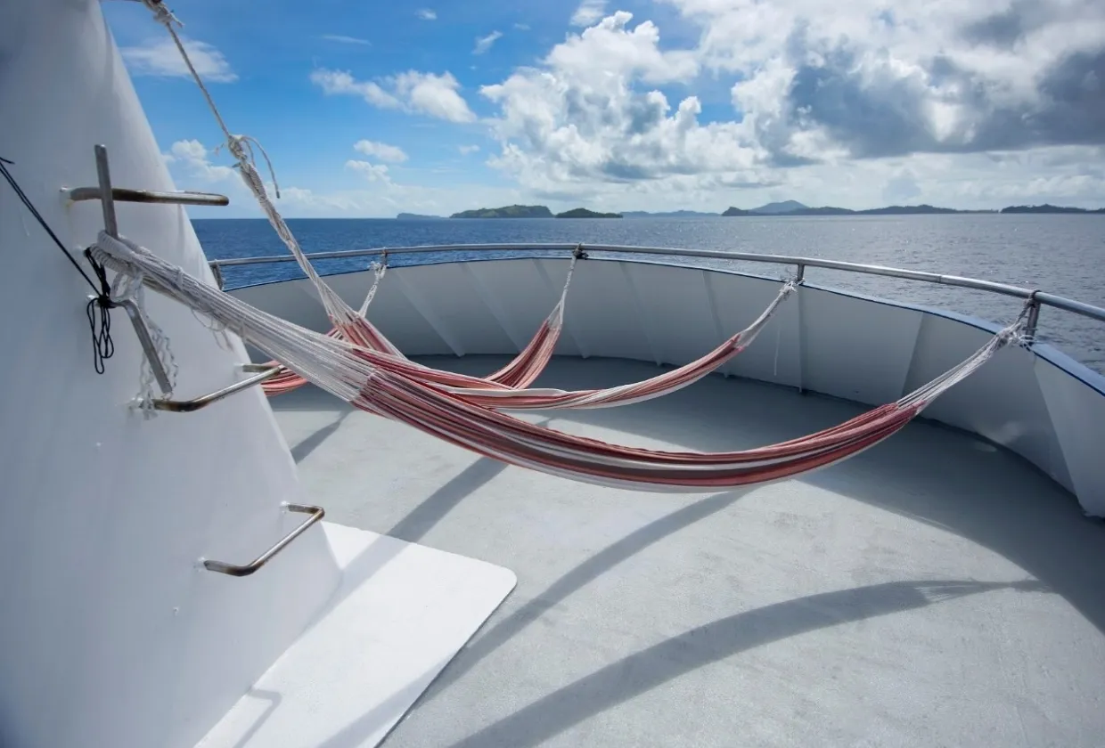 Hammocks on the bow deck of Pacific Master with islands on the horizon
