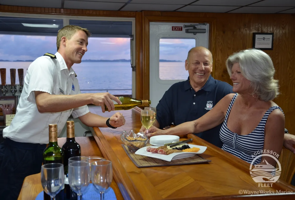 The captain pours wine at dinner on board