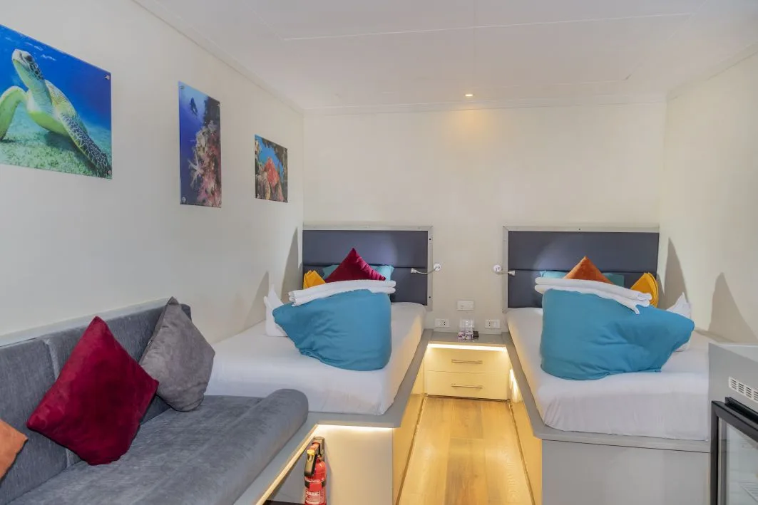 Master Twin cabin — beds, sofa and reef prints on the wall