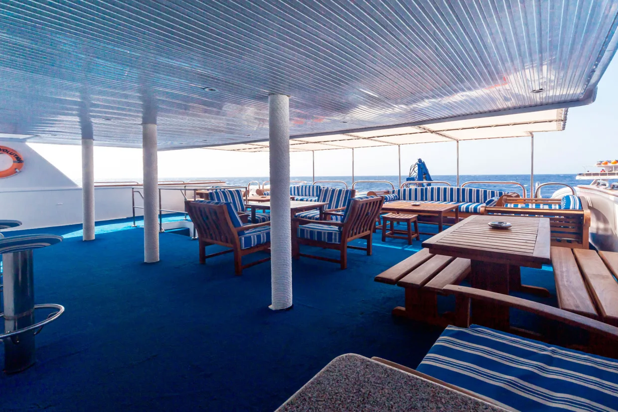 Teak sofas and tables on the shaded deck of Royal Evolution