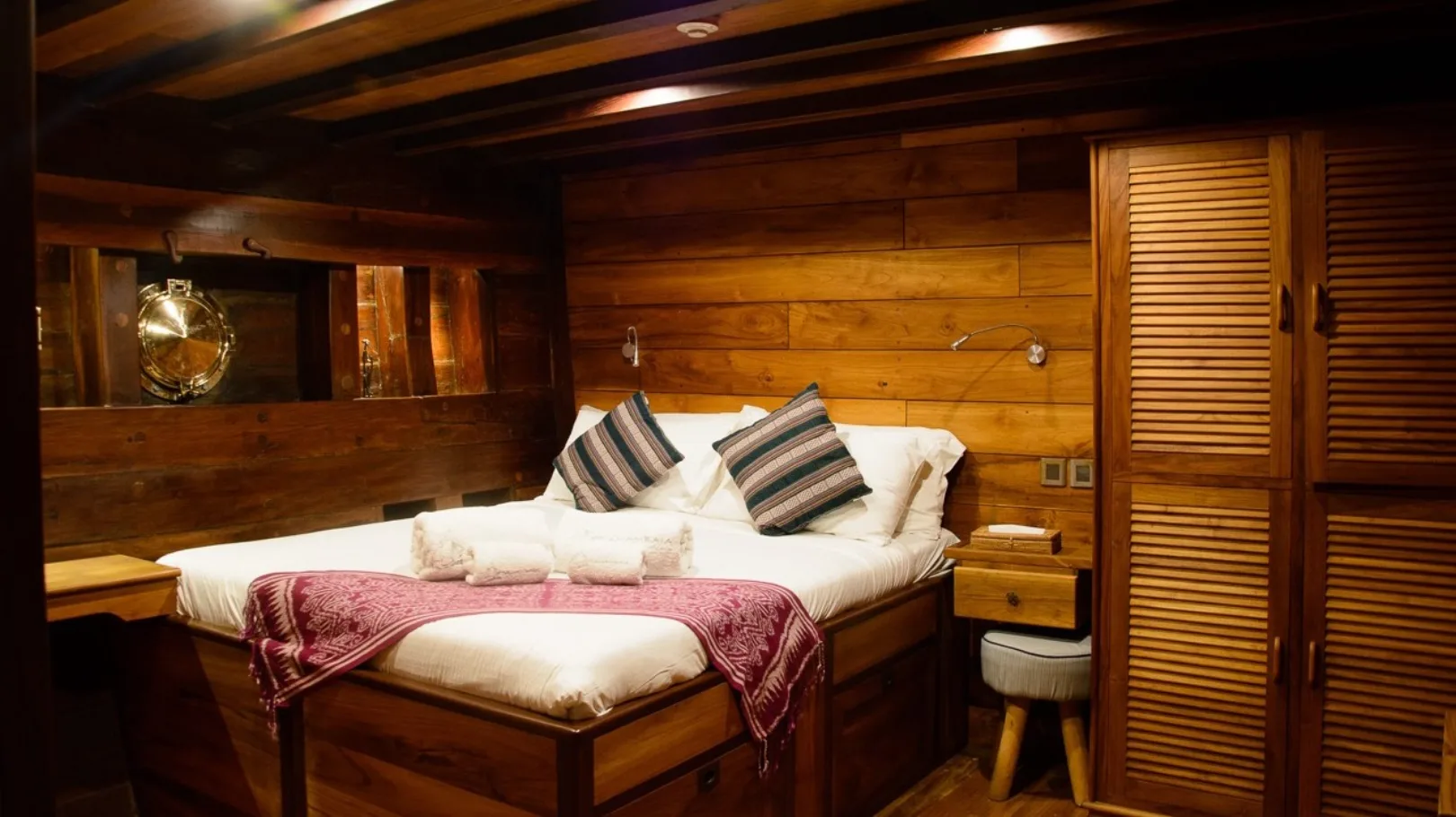 Cabin 1 in double configuration — teak panelling and a batik bedspread
