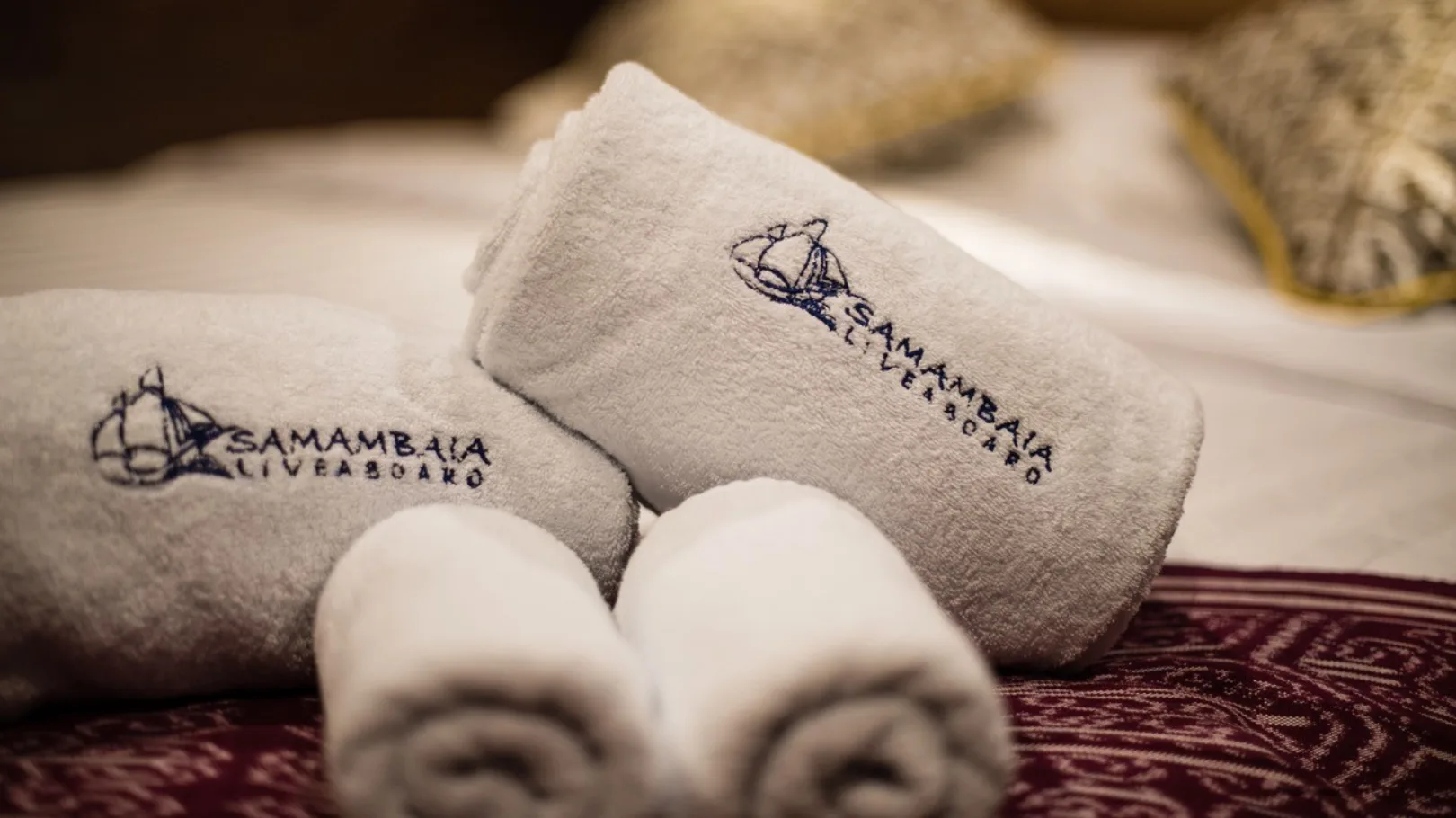 Towels embroidered Samambaia Liveaboard and batik on the bed