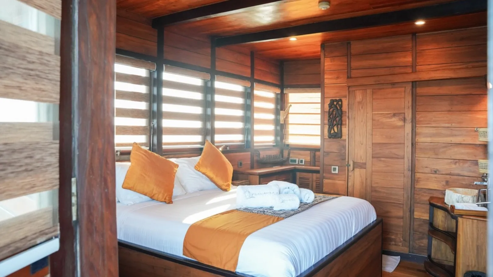 Another angle of the master cabin, teak panelling and orange cushions