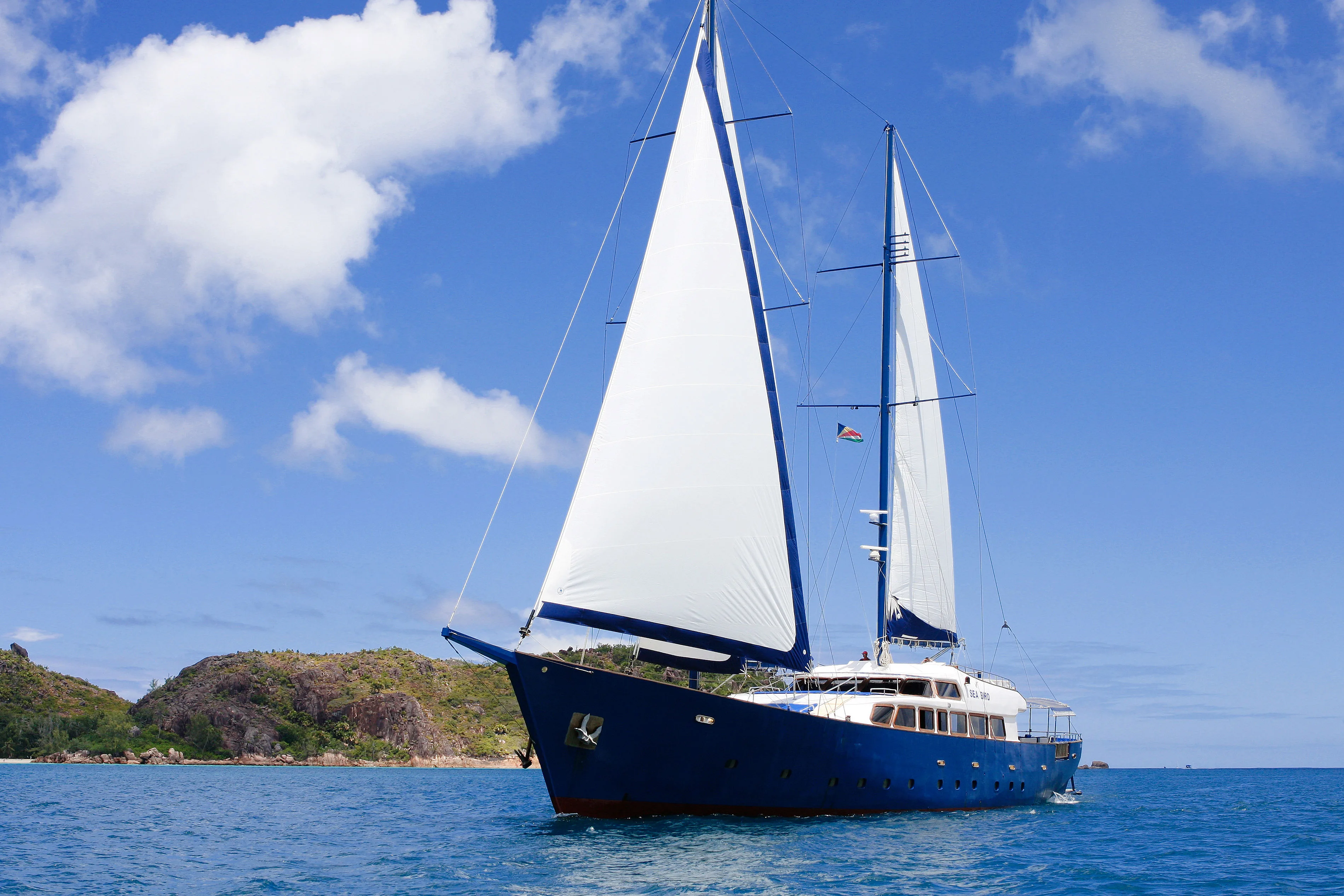 The two-masted silhouette of Sea Bird in a turquoise bay