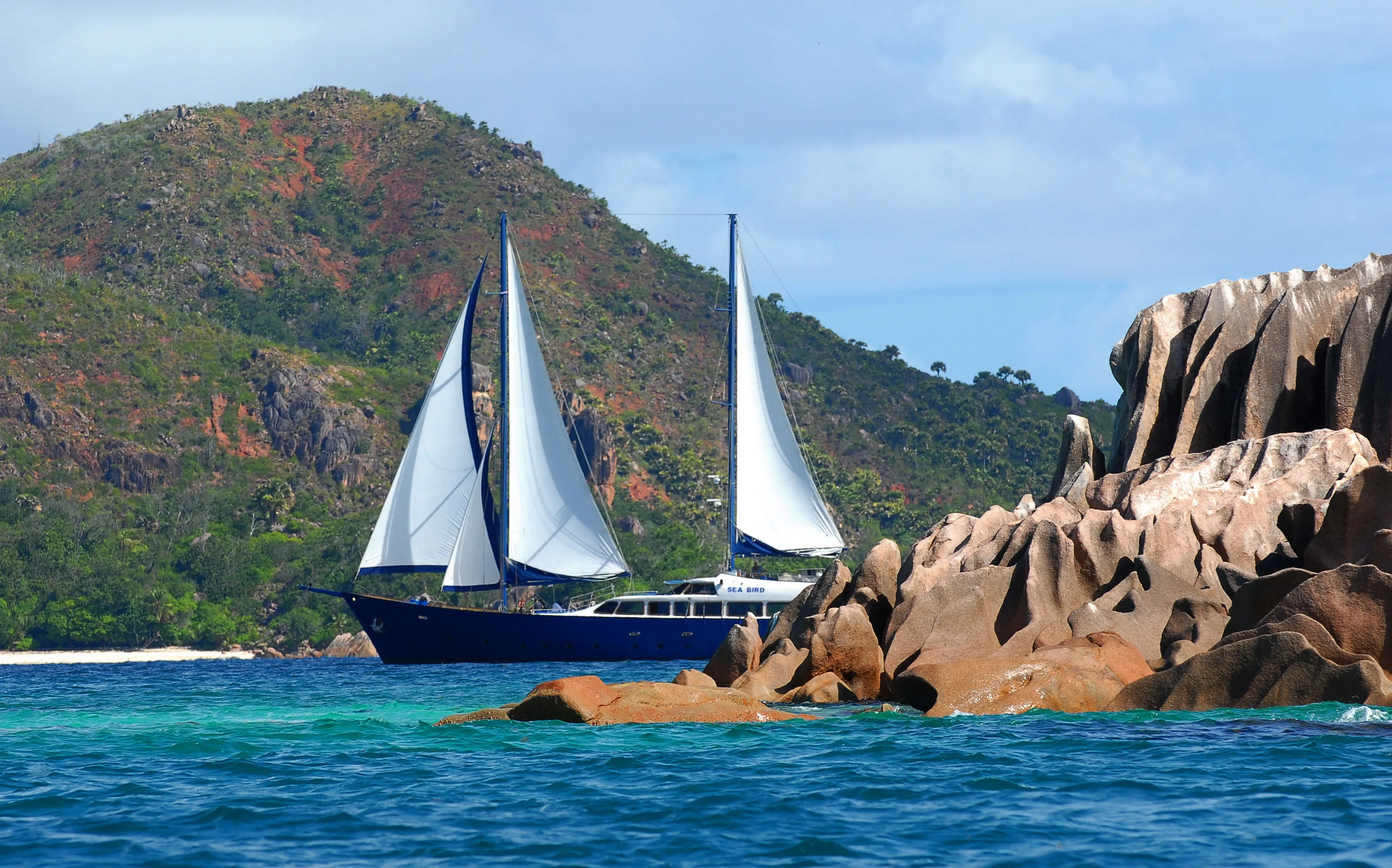 Sea Bird passing the granite boulders of La Digue