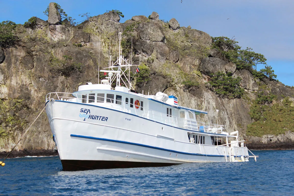 Sea Hunter alongside the rocky shore of Cocos Island