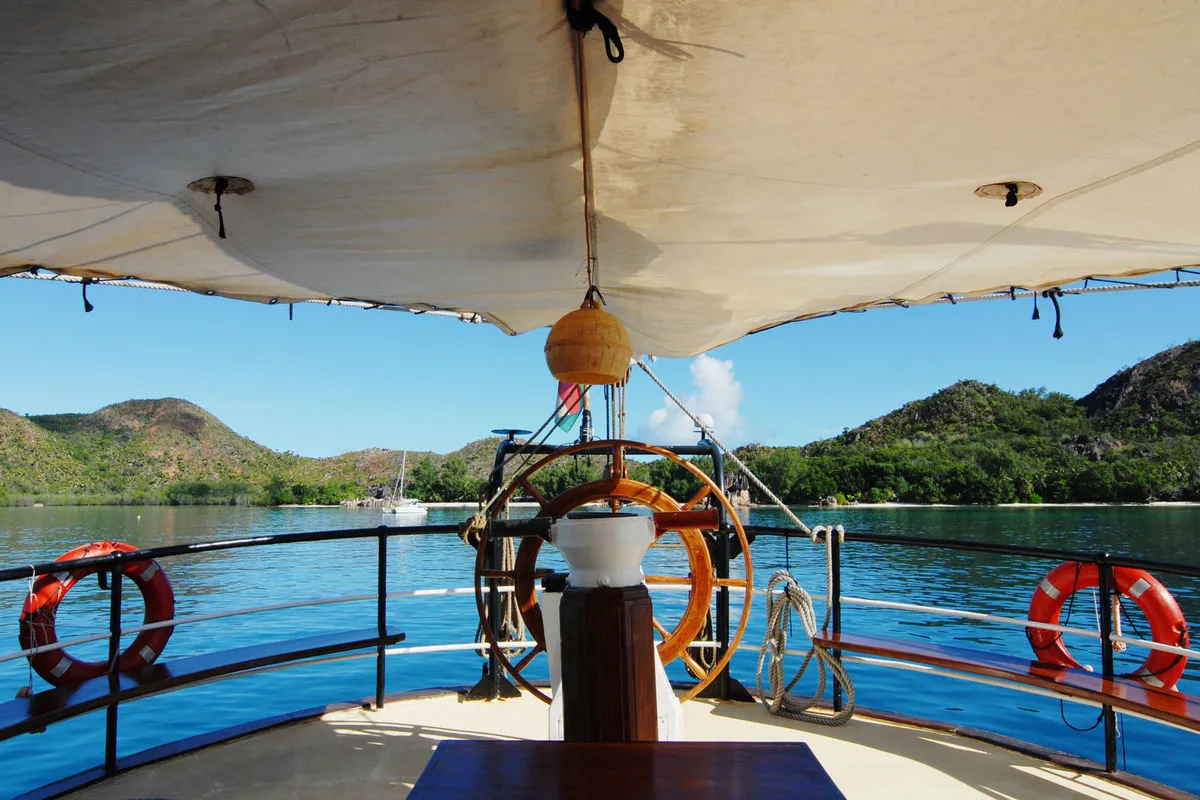 The wheel of Sea Pearl under a canvas awning on the aft deck