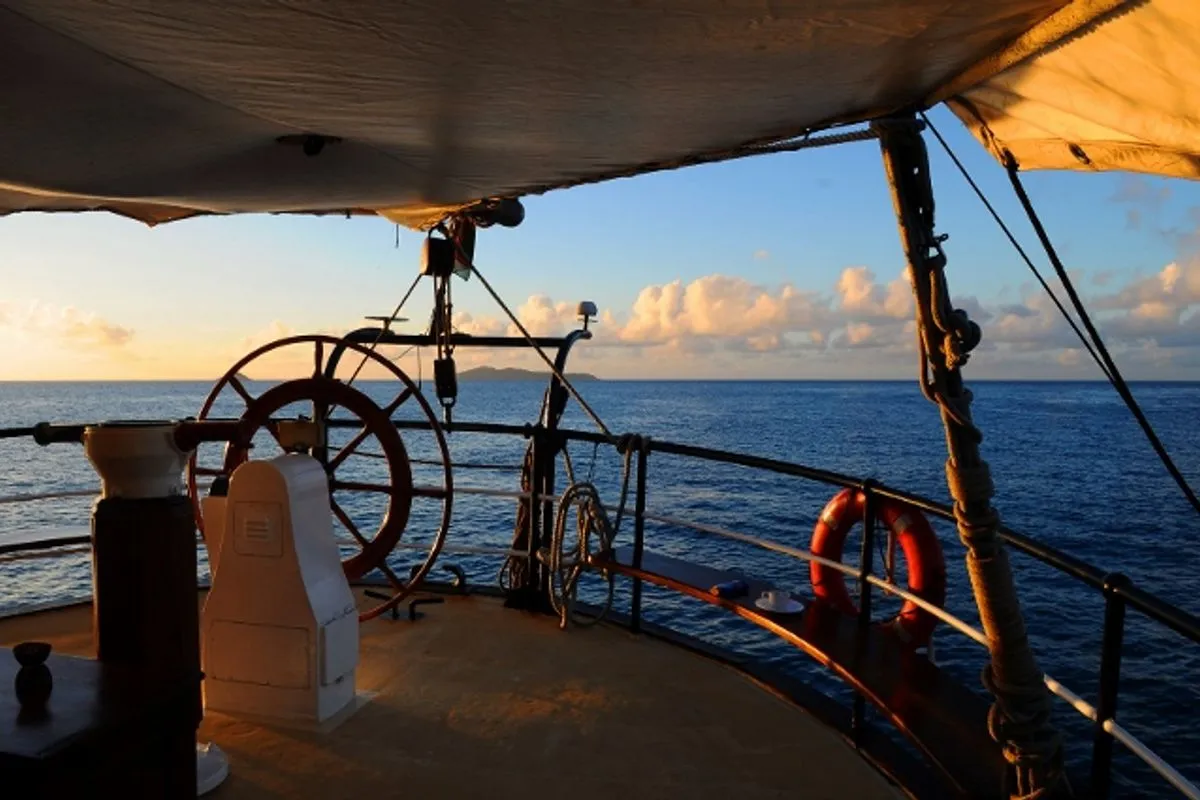 The aft deck of Sea Pearl at dawn, wheel and life ring in the light