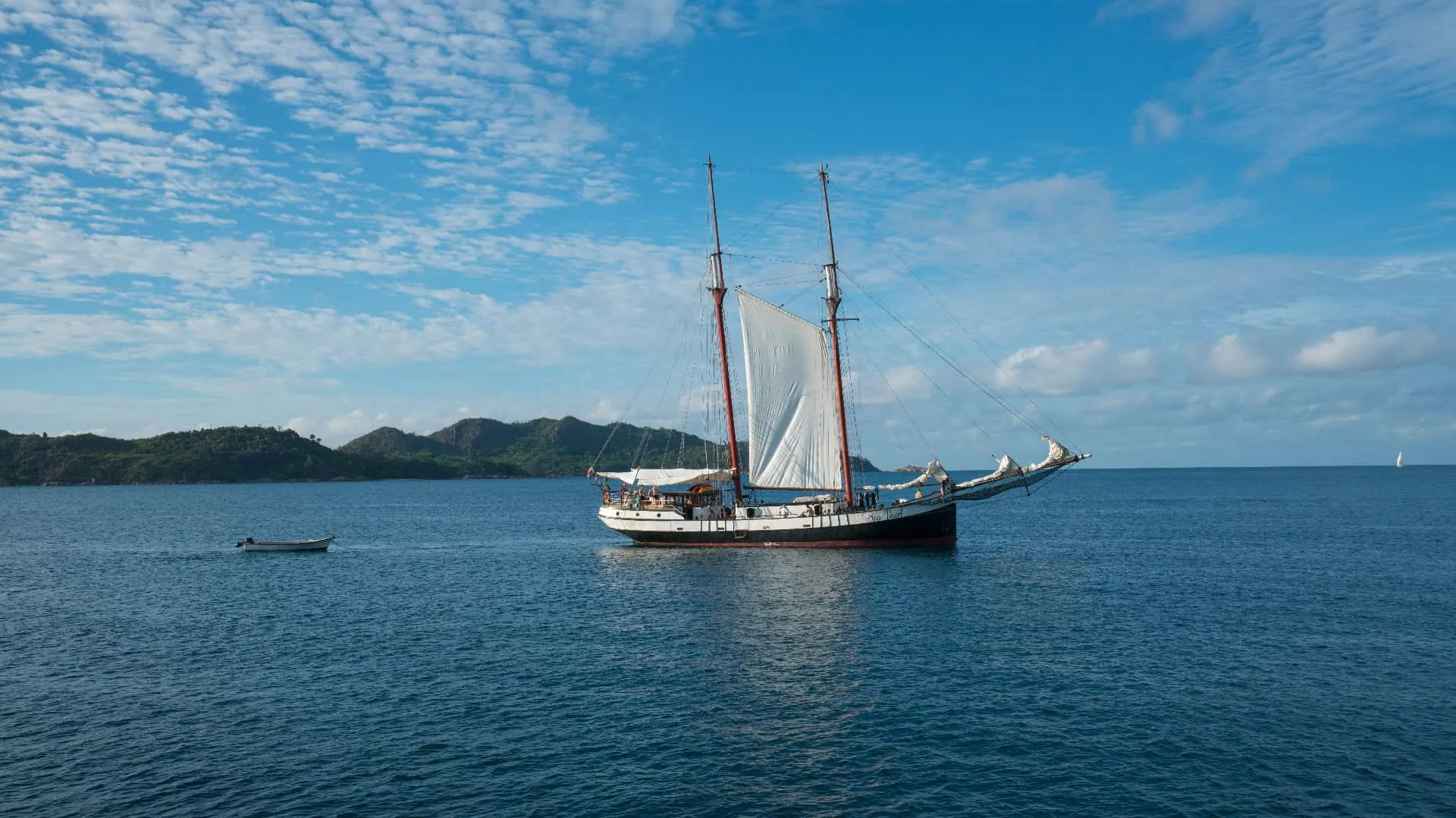 Sea Pearl anchored off the shore with her tender alongside