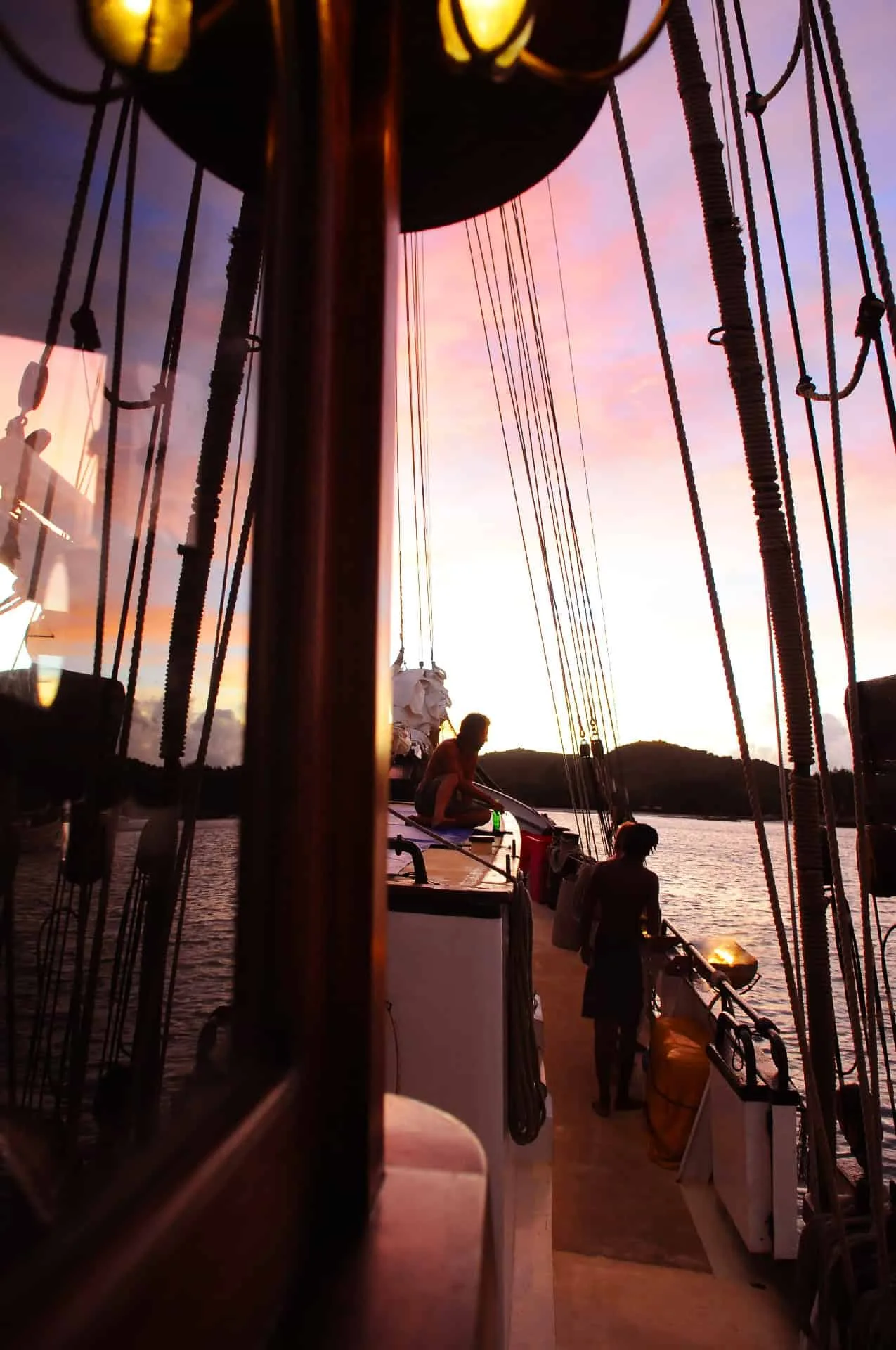 Guests on the deck of Sea Pearl among the rigging in pink dusk
