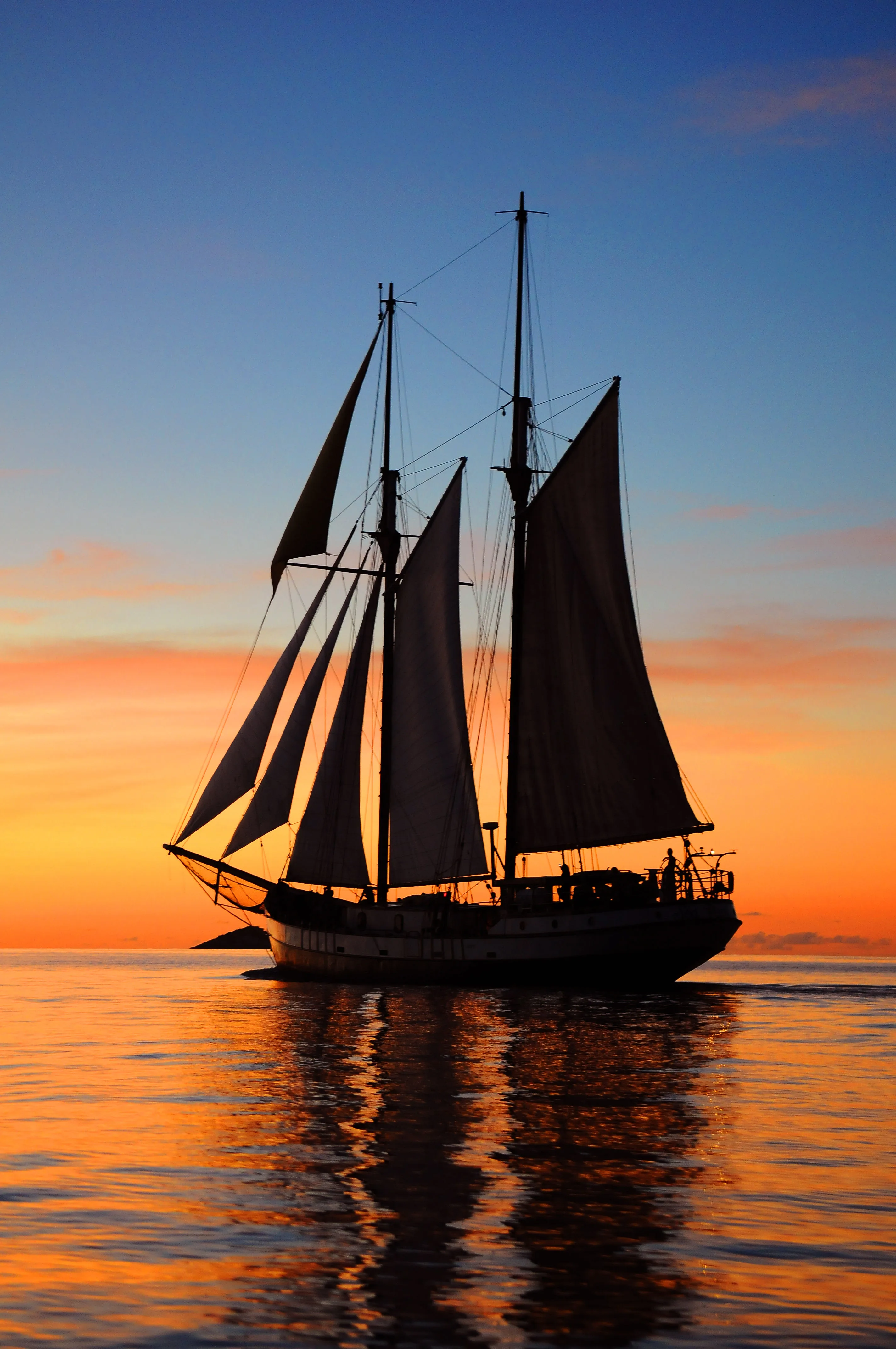 Silhouette of the two-masted schooner against an orange sky
