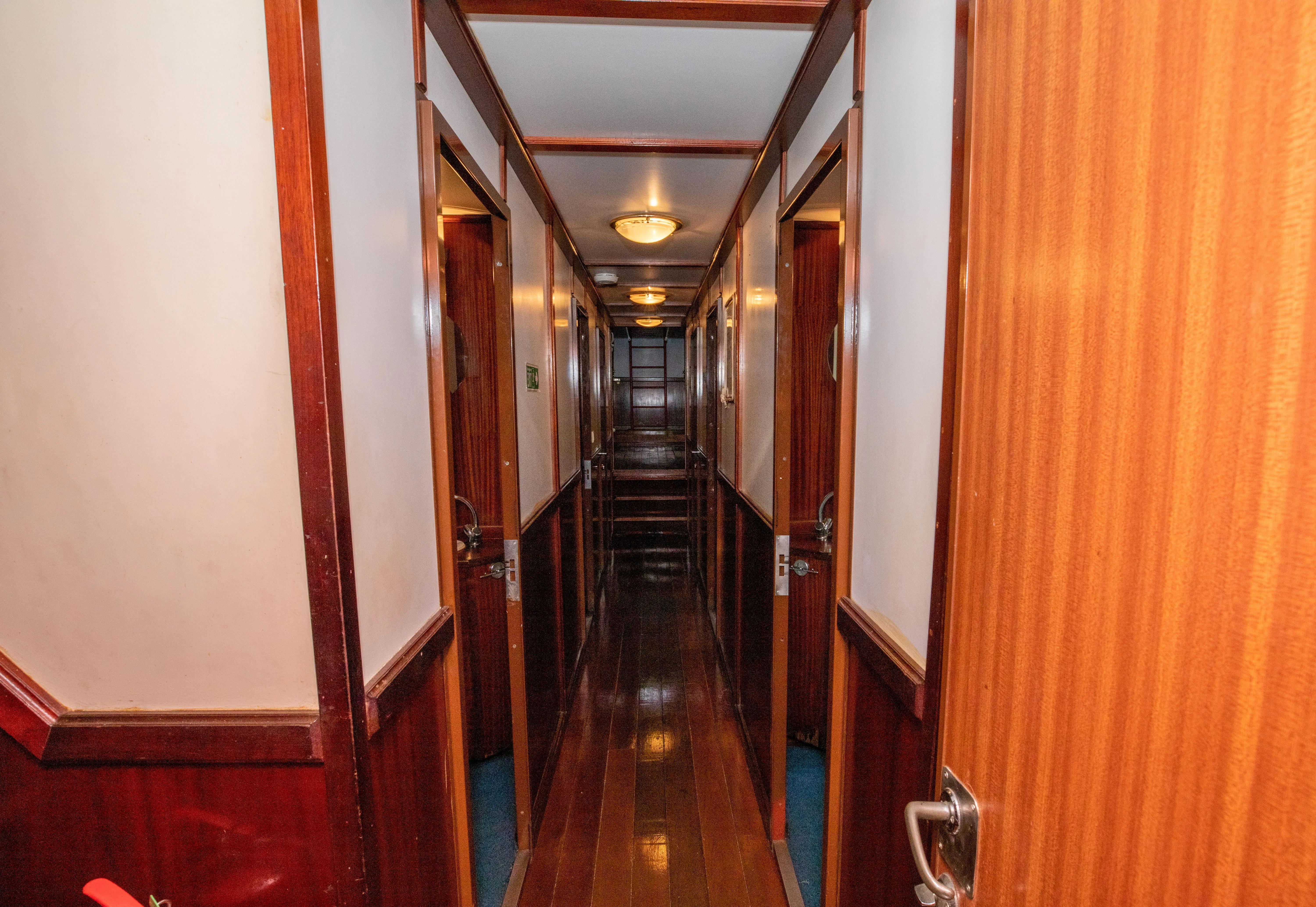 The lower deck corridor of Sea Pearl lined with mahogany cabin doors