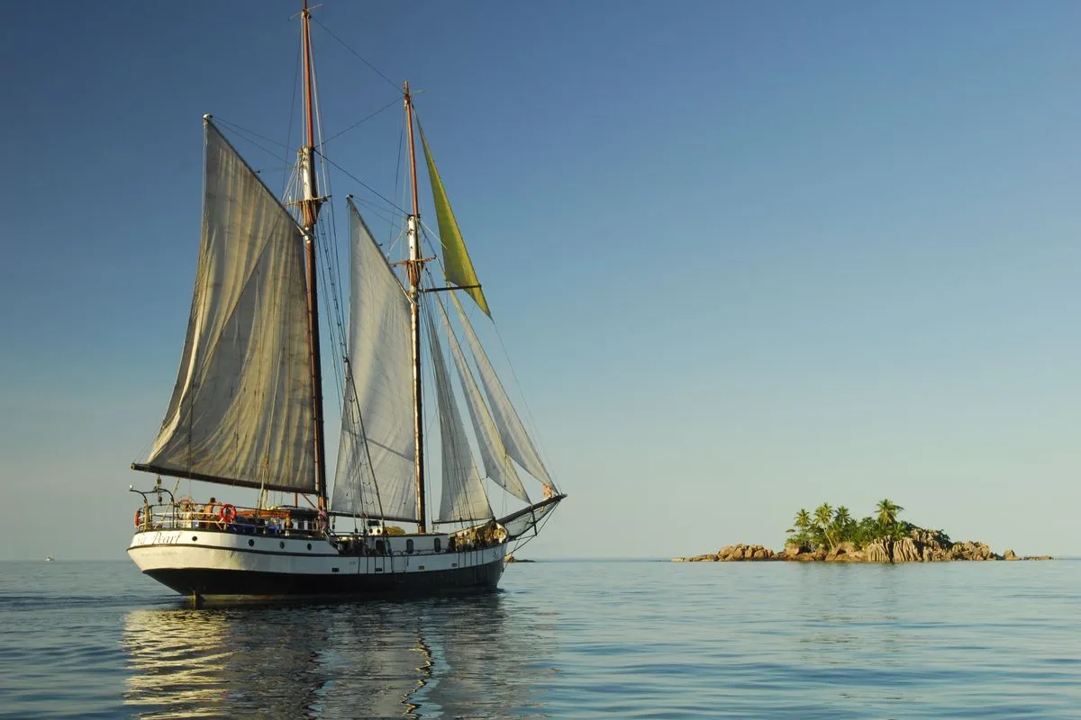 The schooner Sea Pearl under sail beside a granite islet in the Seychelles