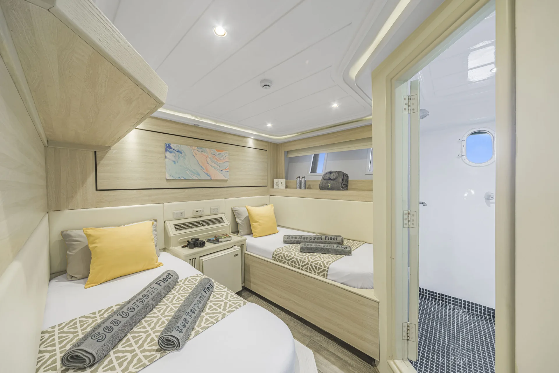 Каюта Standard Twin на нижней палубе Sea Serpent Grand — две кровати и открытая дверь в санузел с иллюминатором