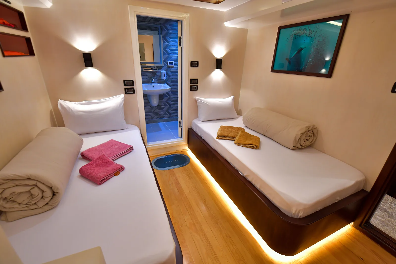 Lower deck cabin with made-up beds and floor-level lighting