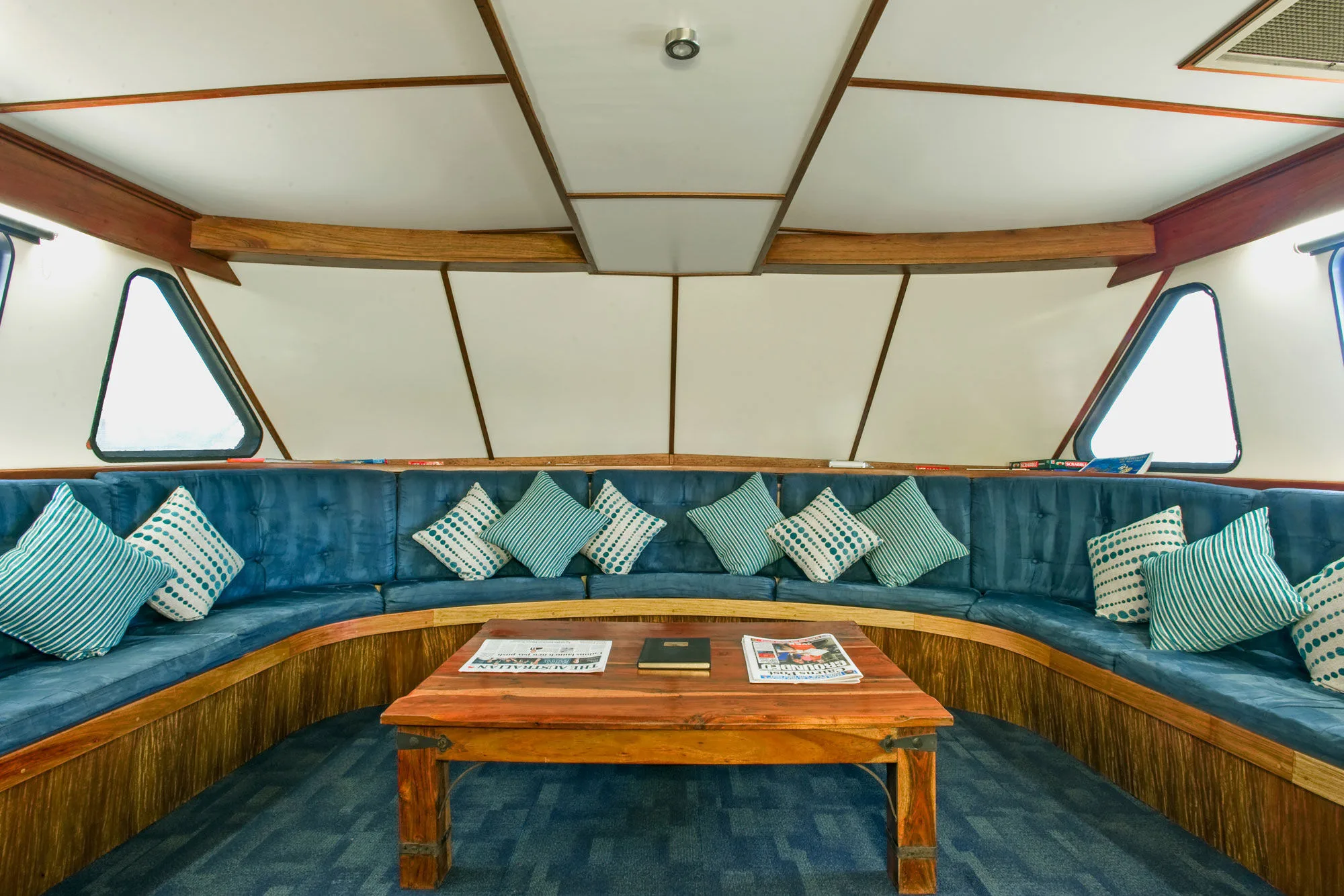The saloon of Spirit of Freedom with blue banquettes and timber trim