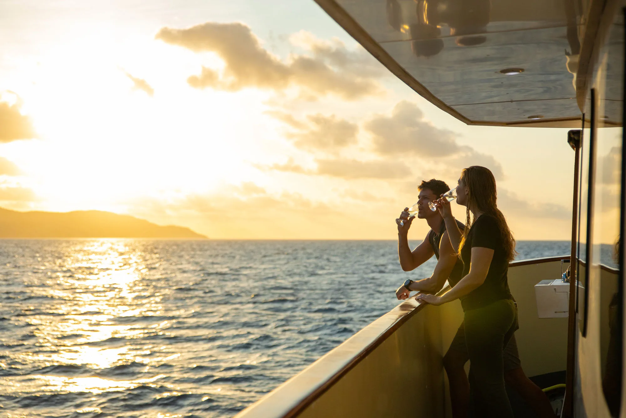 A guest with a drink at the rail at sunset