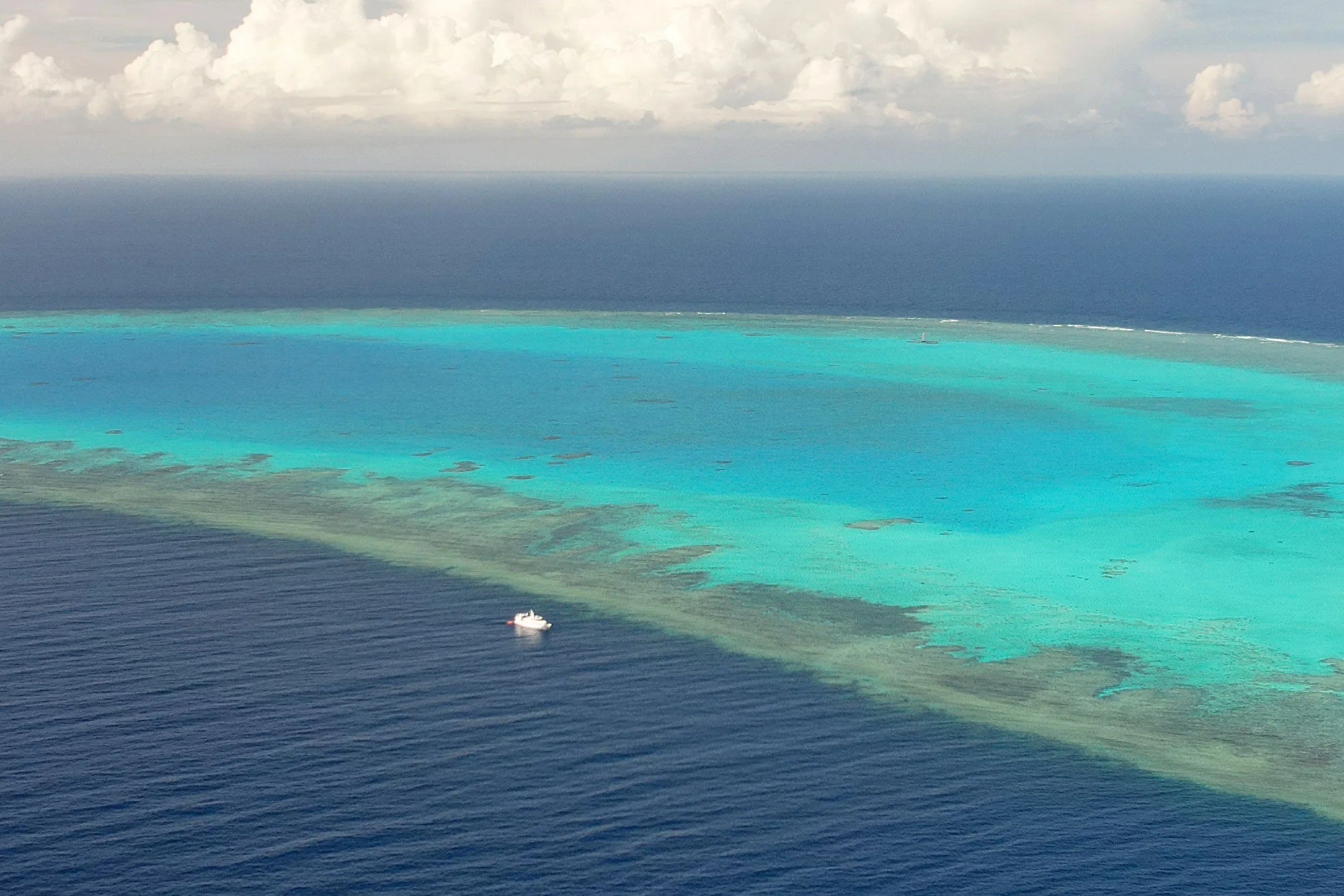 The reef edge from the air with the vessel's wake on the water