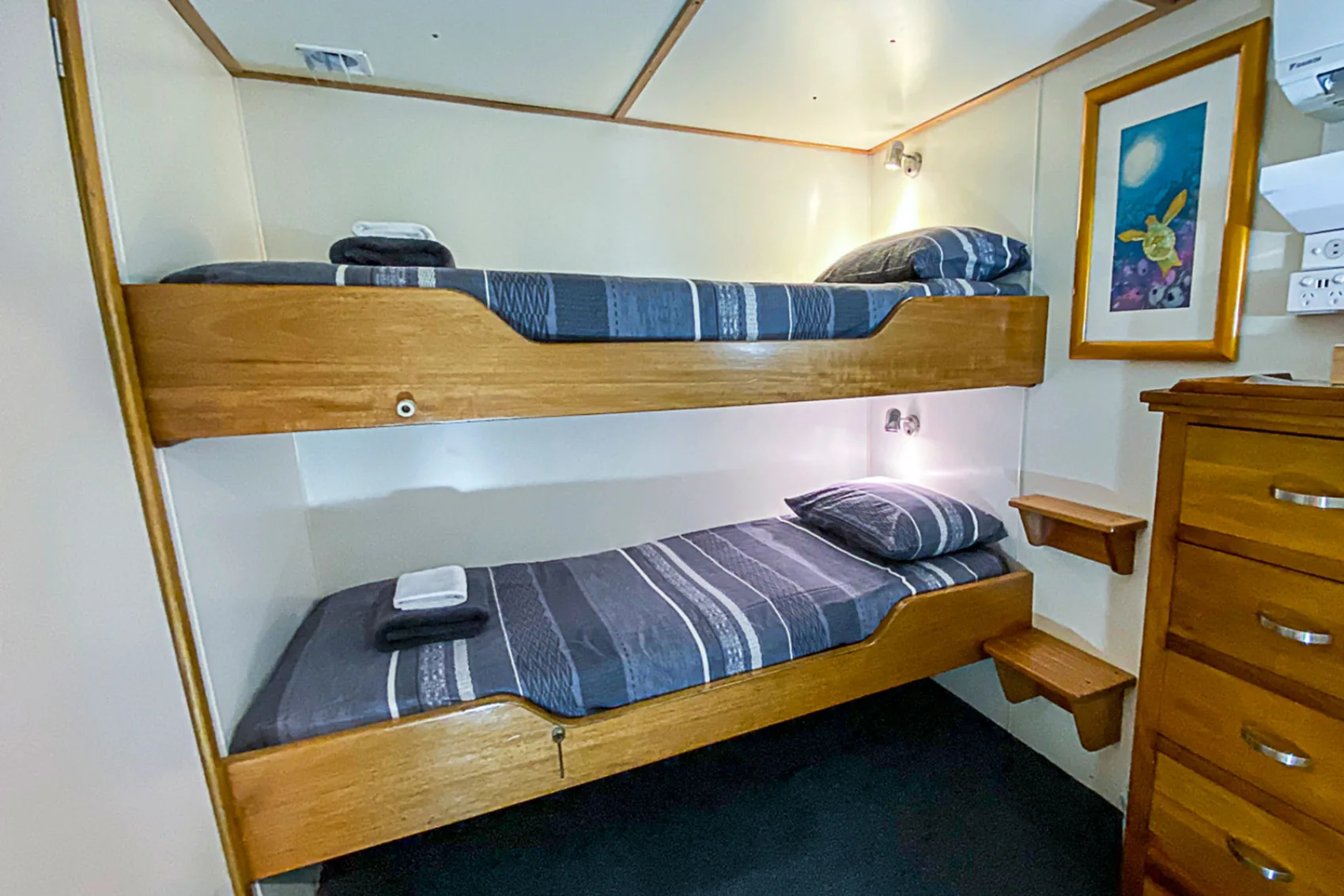 Spoilsport budget cabin — bunk beds and a chest of drawers in the bow