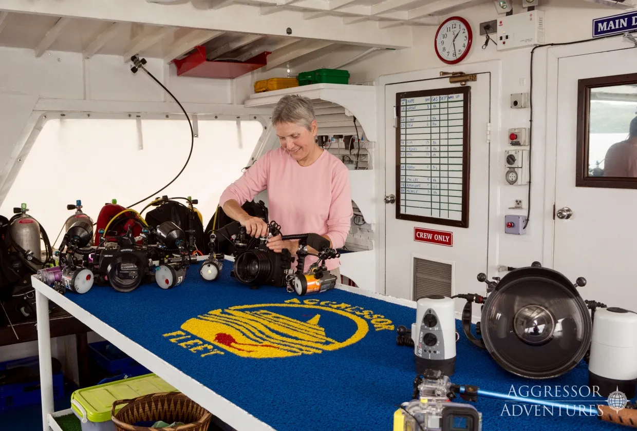 A guest assembling an underwater camera at the camera table of Thailand Aggressor