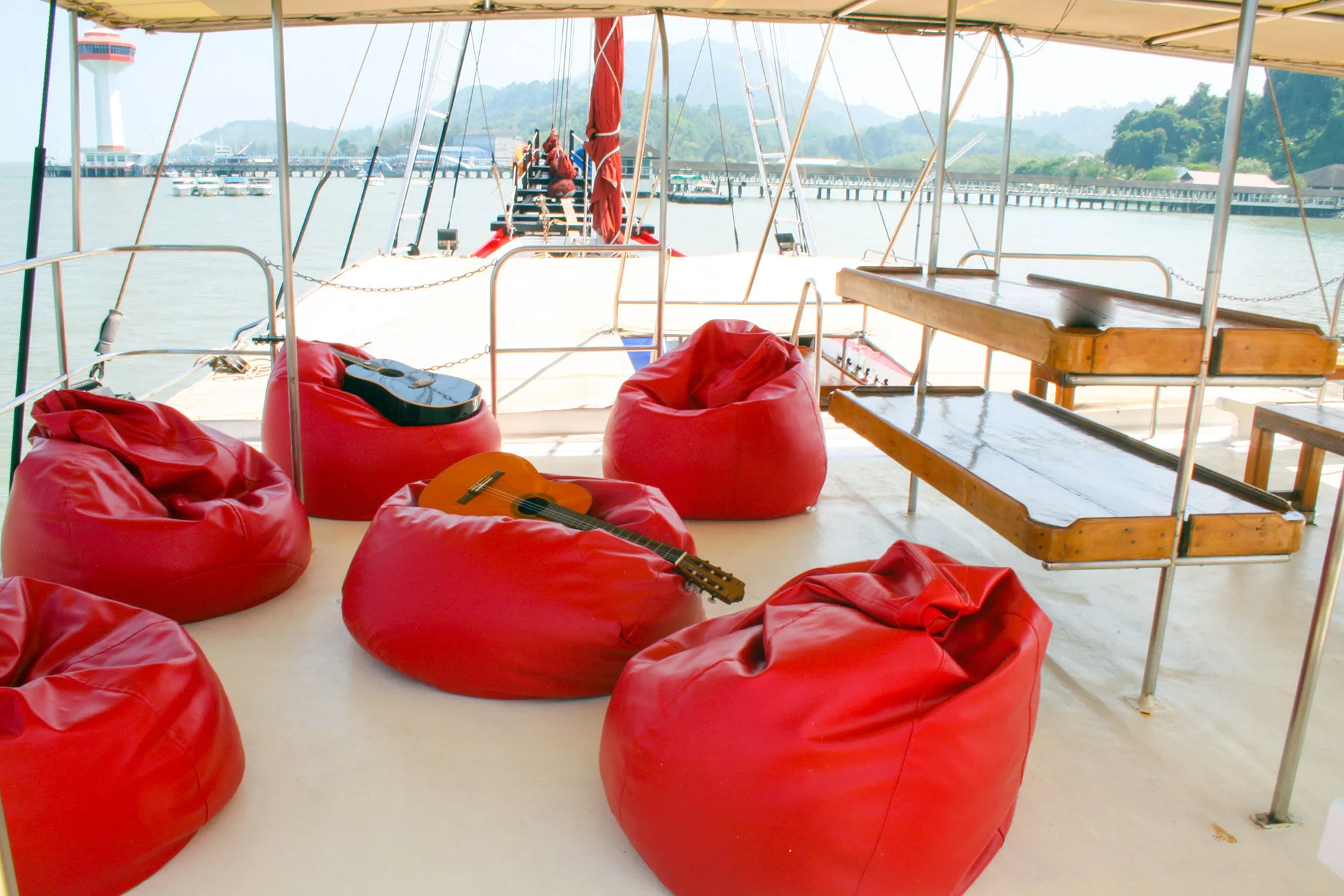 Red bean bags and a guitar on the sundeck of Thailand Master