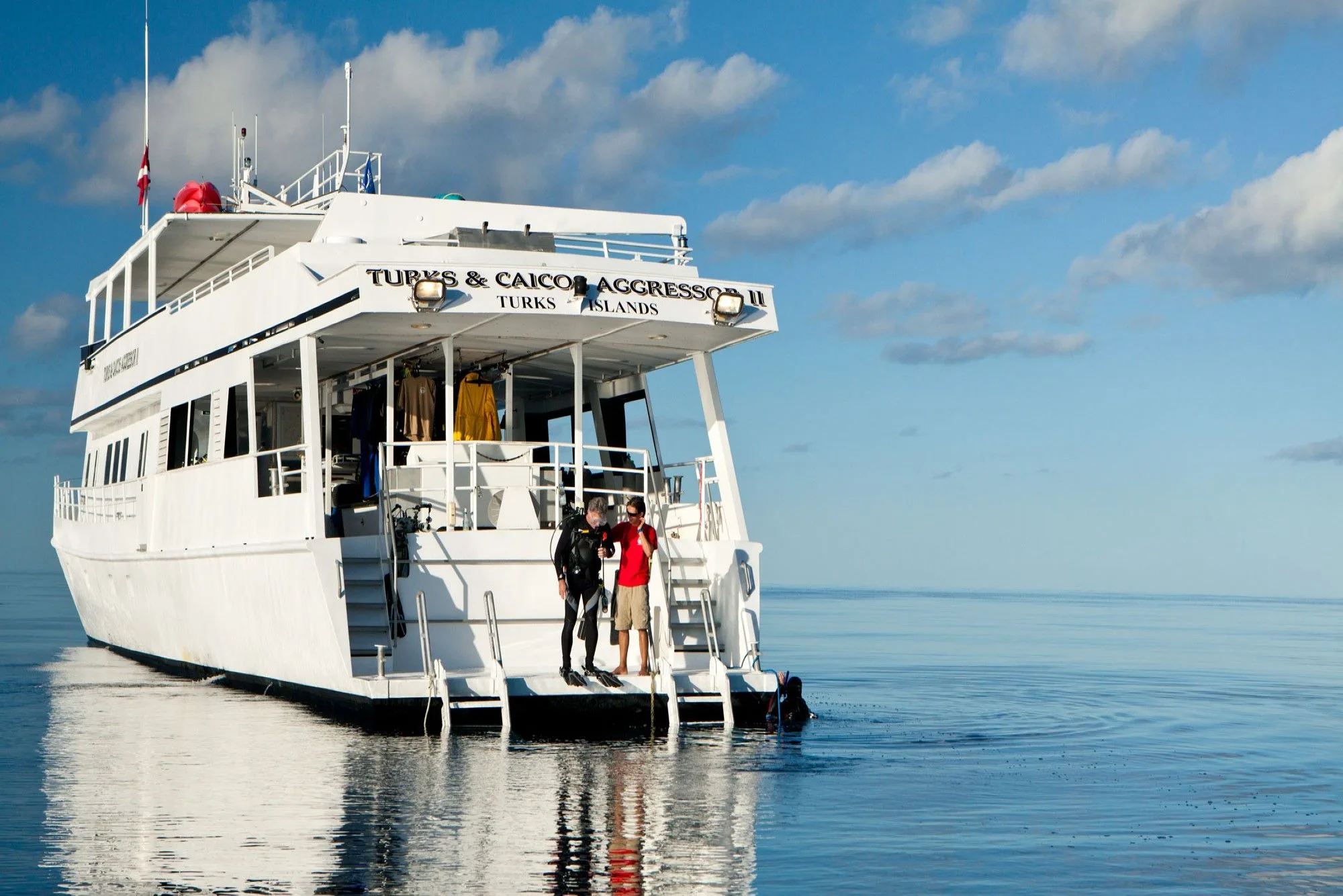 Stern of Turks and Caicos Aggressor II with the dive platform and guests on the ladder