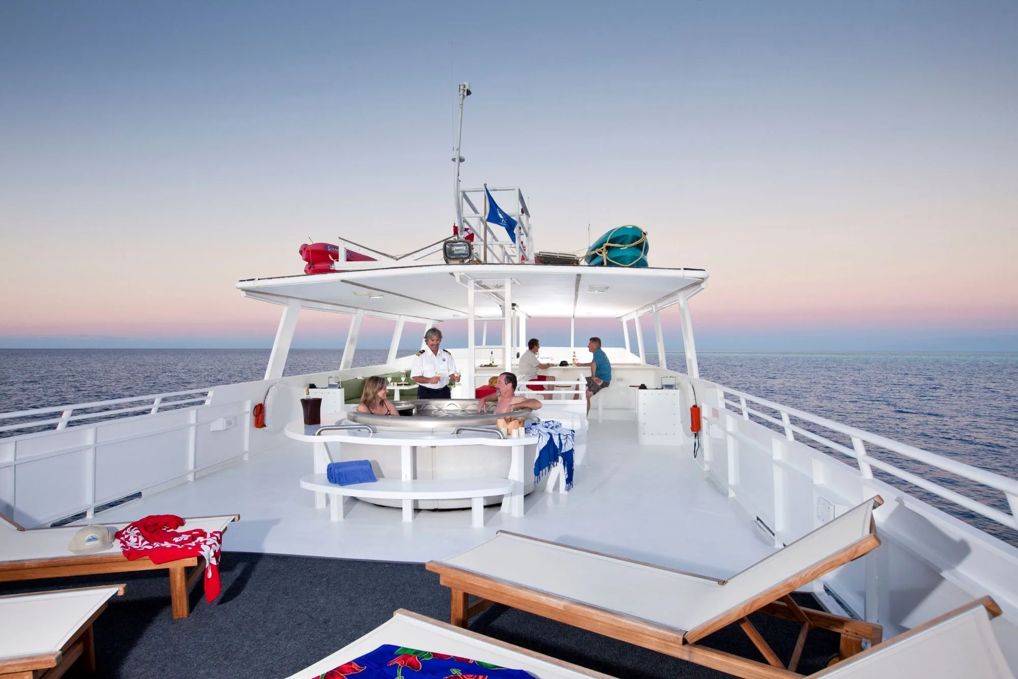 Sun deck of Turks and Caicos Aggressor II at dusk with loungers and the wet bar