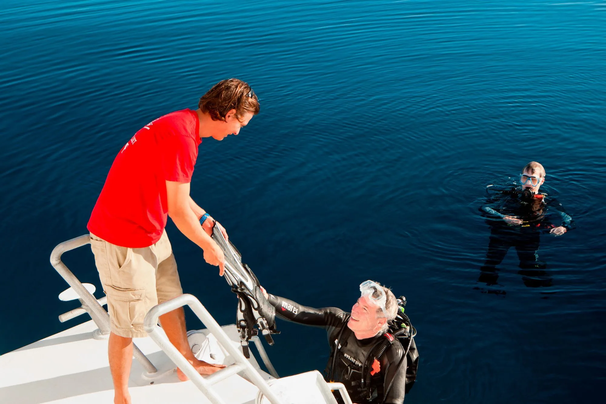 Crew member taking gear from a diver at the platform