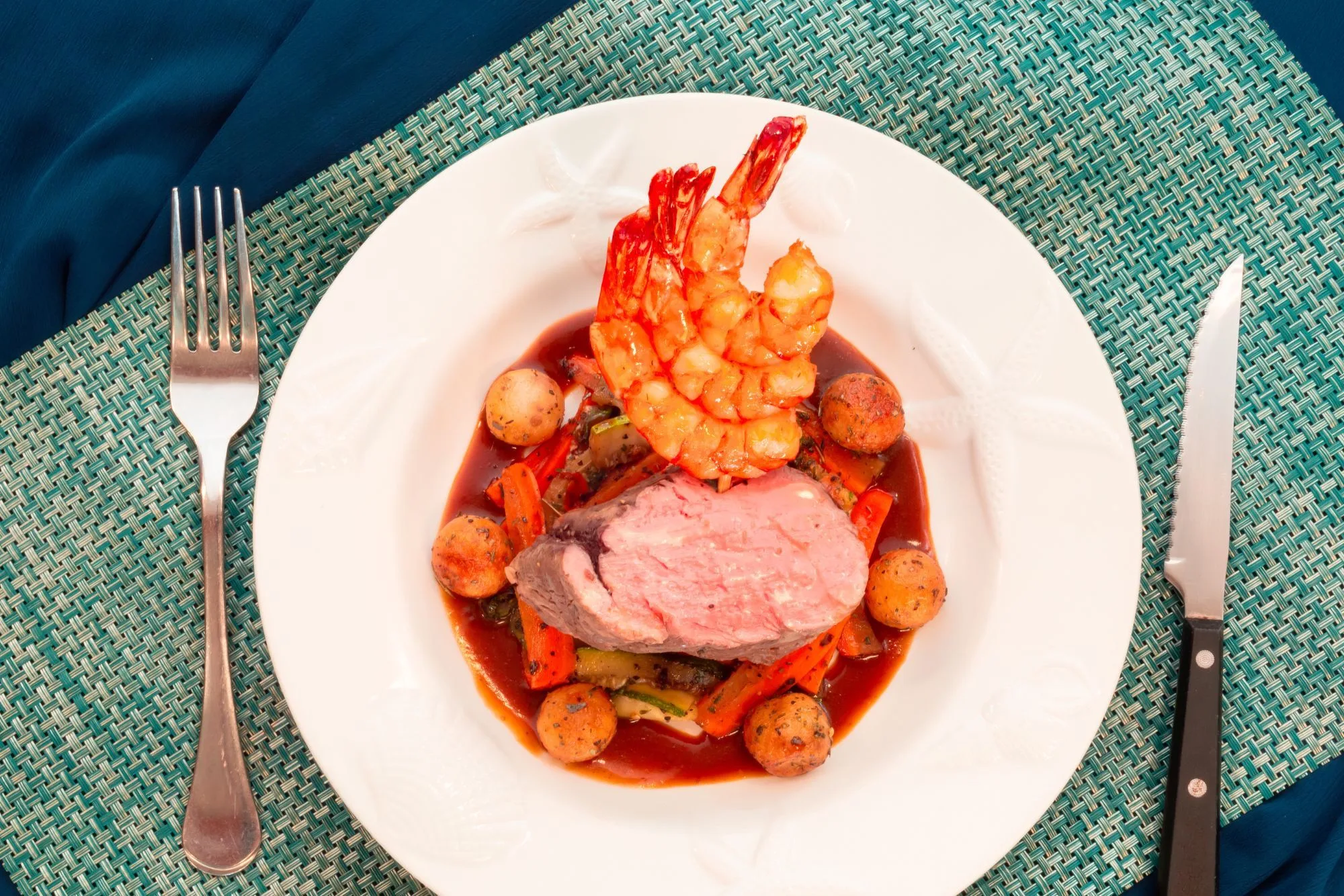 Plated dinner on board — beef with a prawn and new potatoes