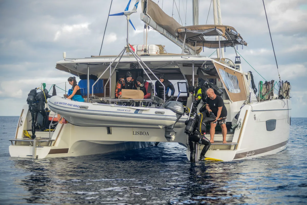 Дайверы уходят в воду с кормовой платформы, лодка RIB рядом