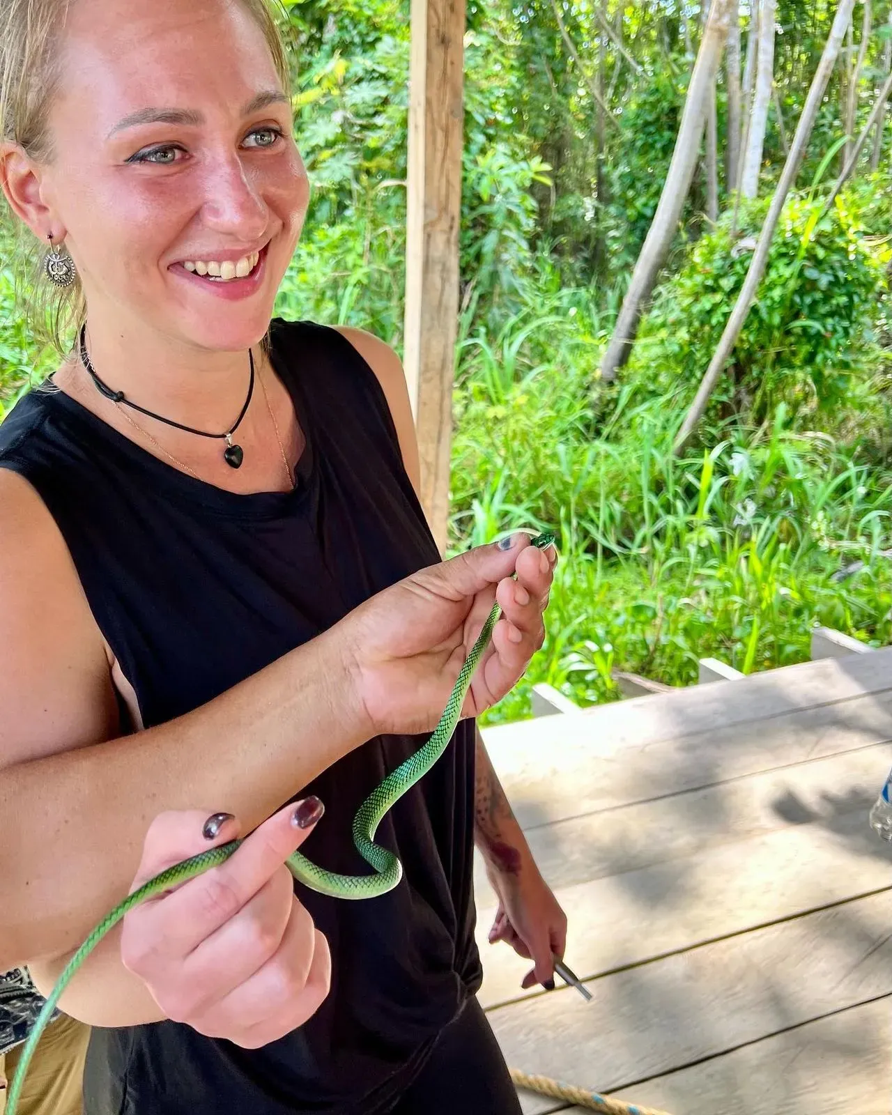 Кристина держит зелёную змею в джунглях