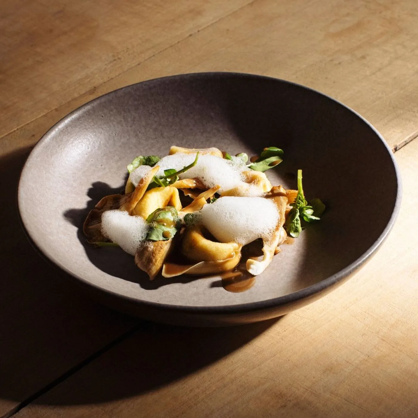 Блюдо ресторана Brindillas — грибы, зелень и пена на керамической тарелке