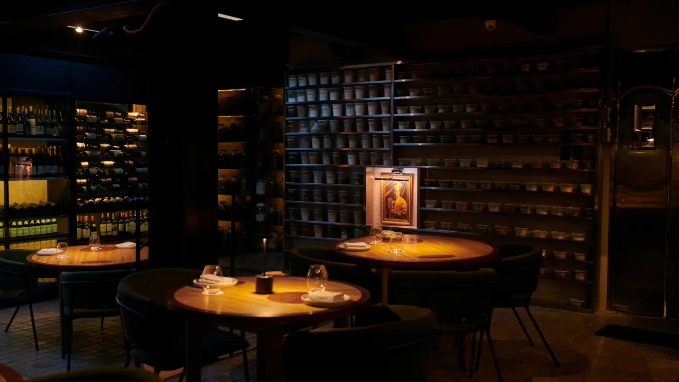 El Chato — камерный зал с полками керамики, тёплый свет свечей на круглых столах