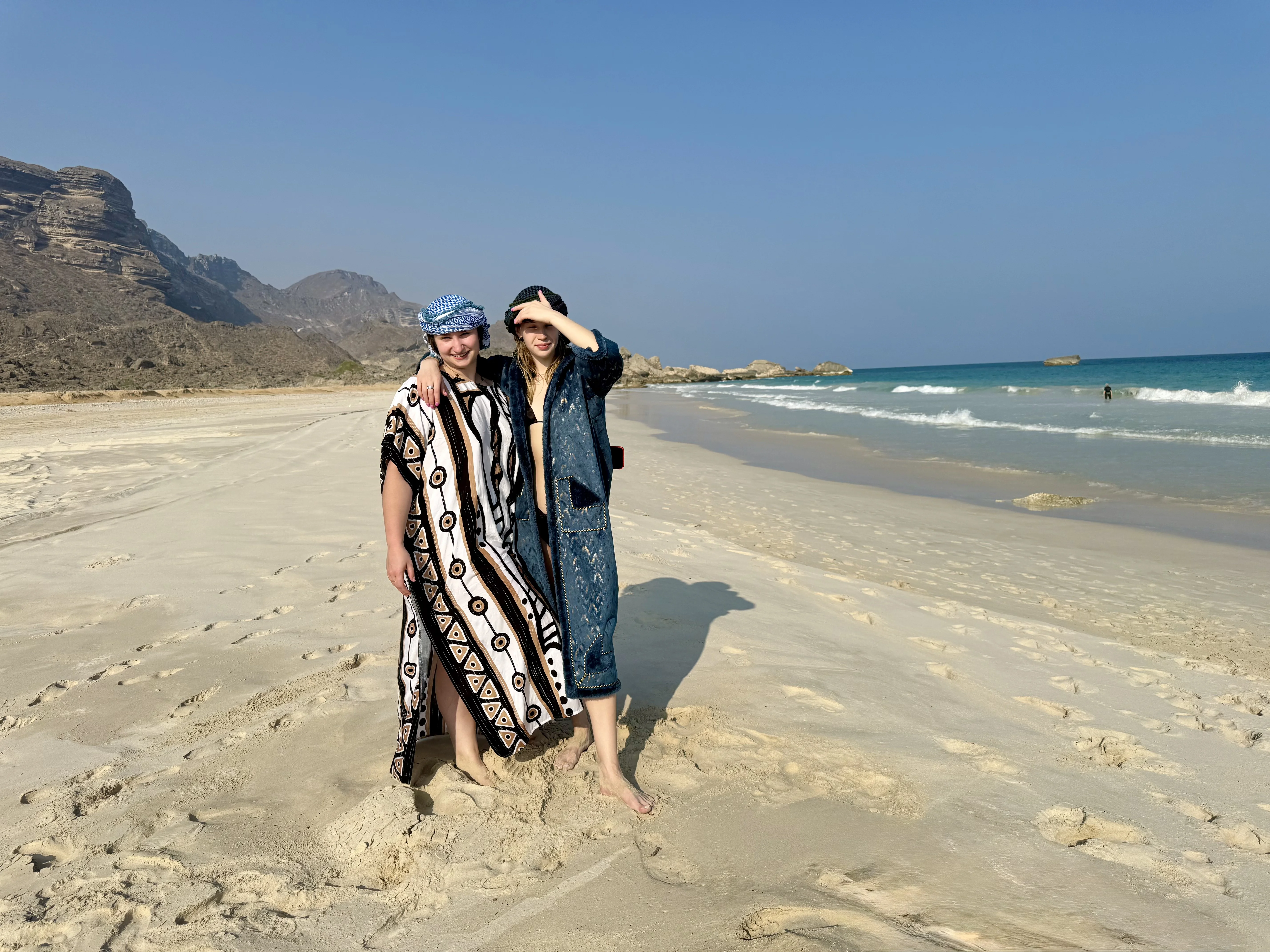 Две девушки на диком пляже Дофара — белый песок, горы, океан