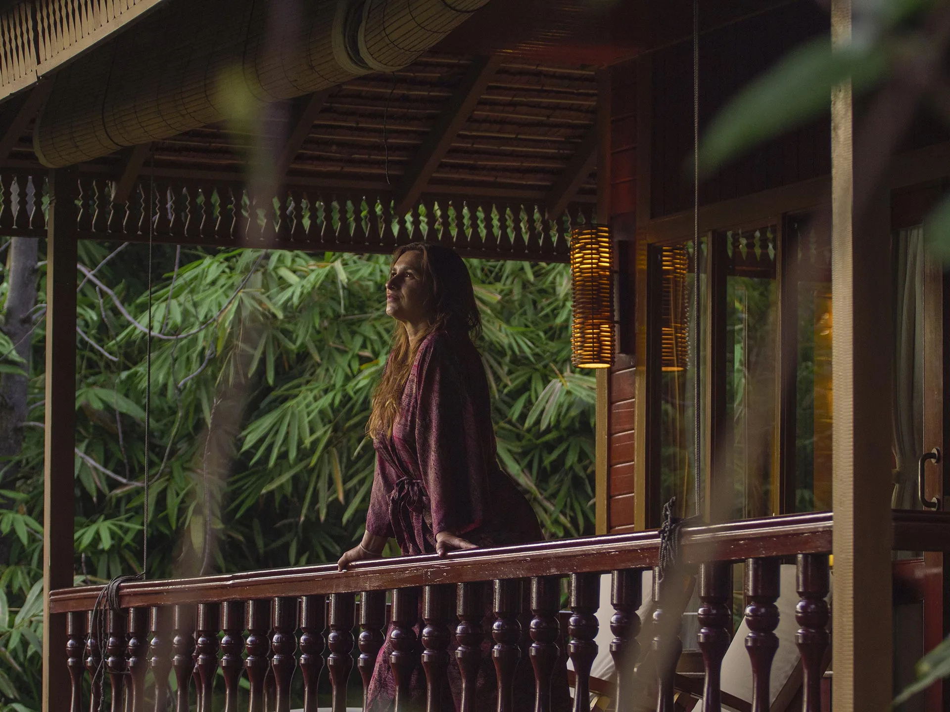 Guest on a cottage veranda surrounded by tropical greenery
