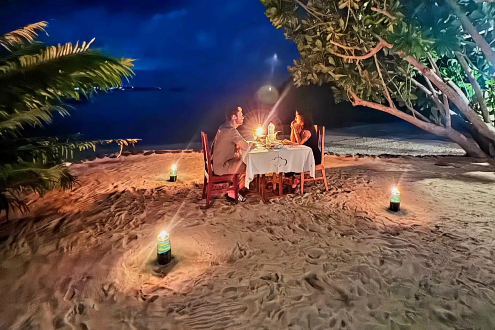 A table on the sand with lanterns at night