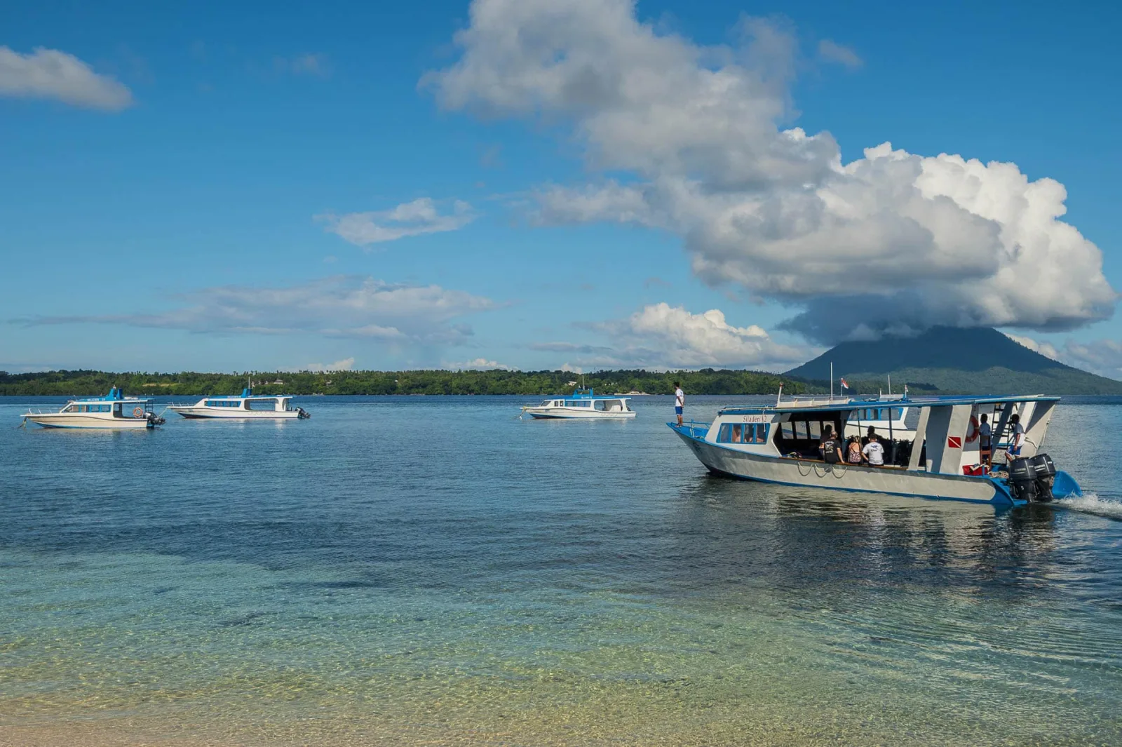 Boats off the shore with the volcano beyond