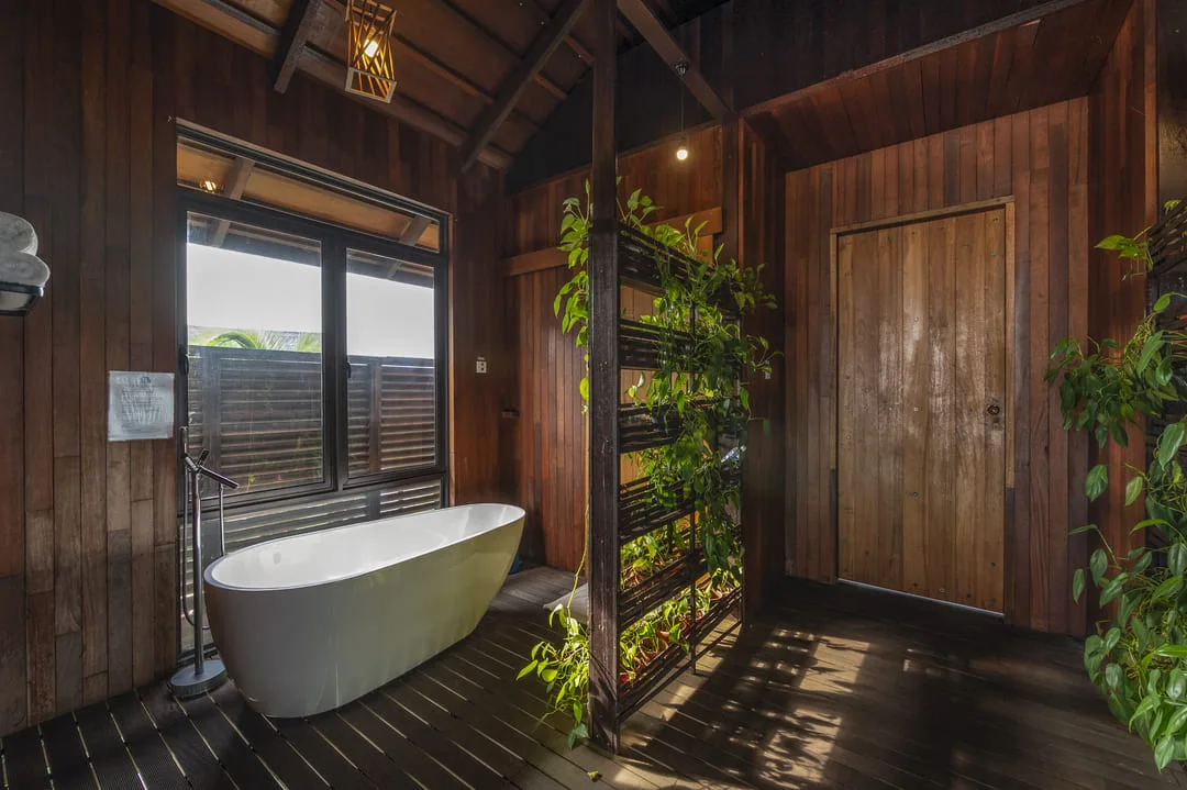 Bathtub with a view of the water and a green wall