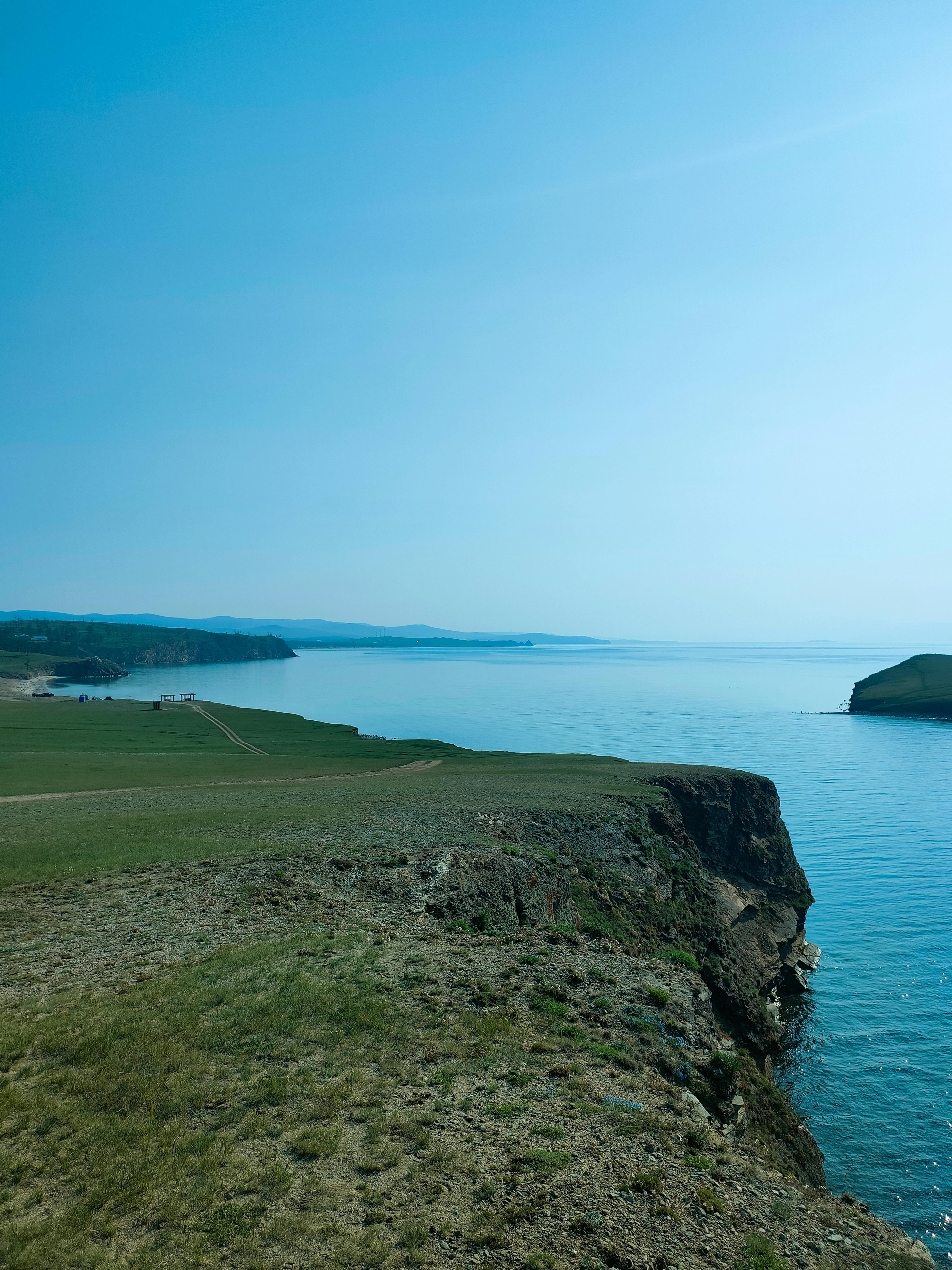 Панорама Байкала — зелёные холмы и скалистый мыс над бирюзовой водой